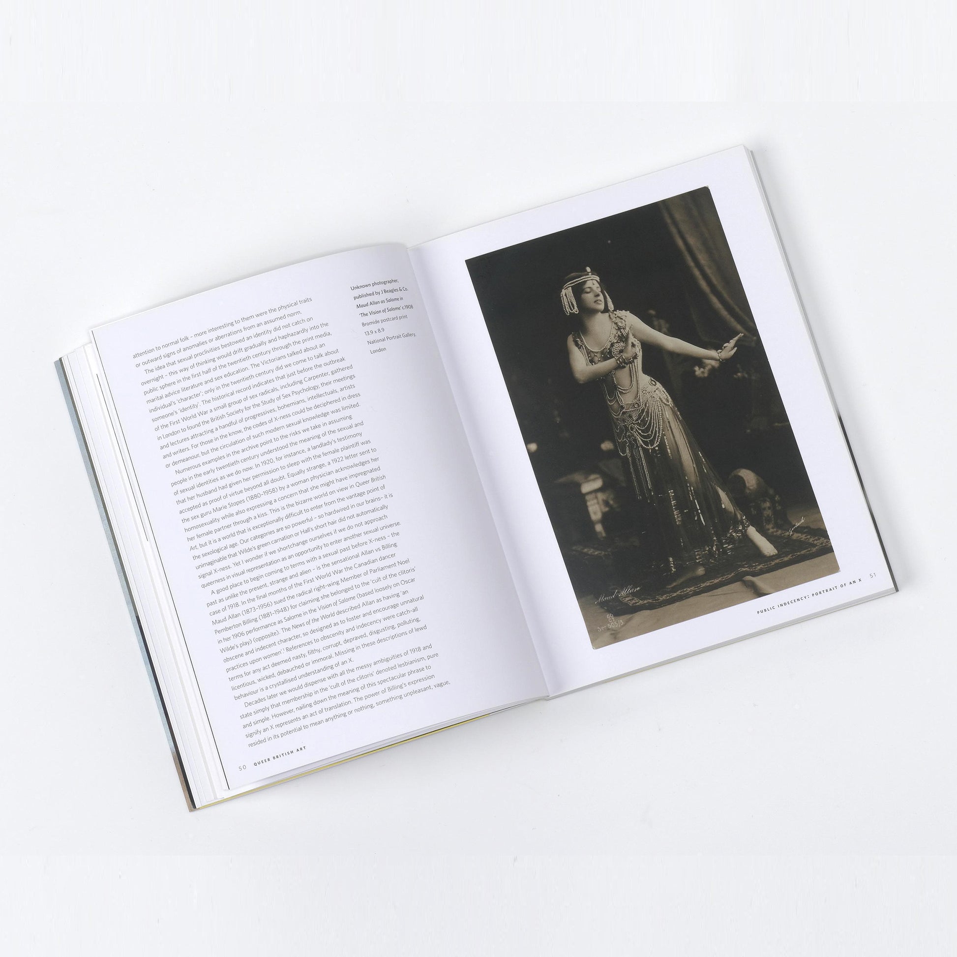Open book spread of Queer British Art, showing a black and white photograph of a theatrical performer in an elaborate costume.
