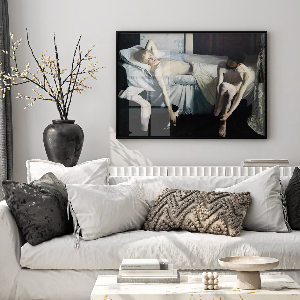 A large framed art print depicting two figures on a bed is displayed on a light gray wall above a white sofa with neutral-toned pillows in a modern living room setting.