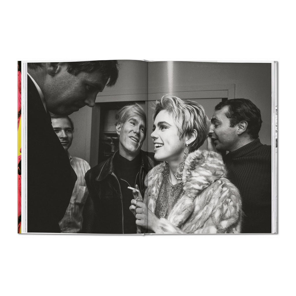 A page spread from the book featuring a black and white fine art photograph by Steve Schapiro of Andy Warhol and Edie Sedgwick at an art opening.