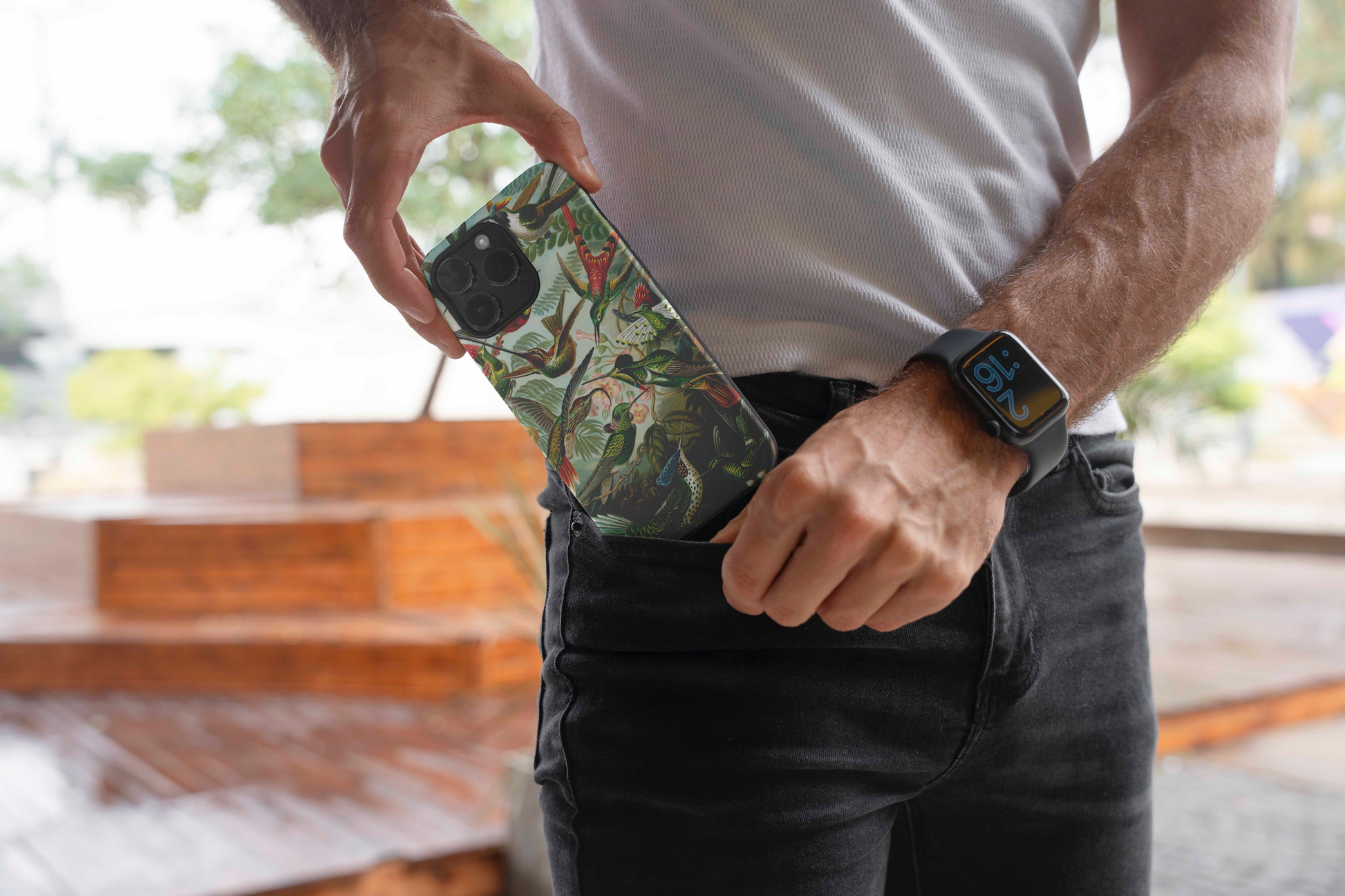 Man placing an iPhone with an Ernst Haeckel hummingbirds fine art phone case into his black jeans pocket, showcasing the phone case design.