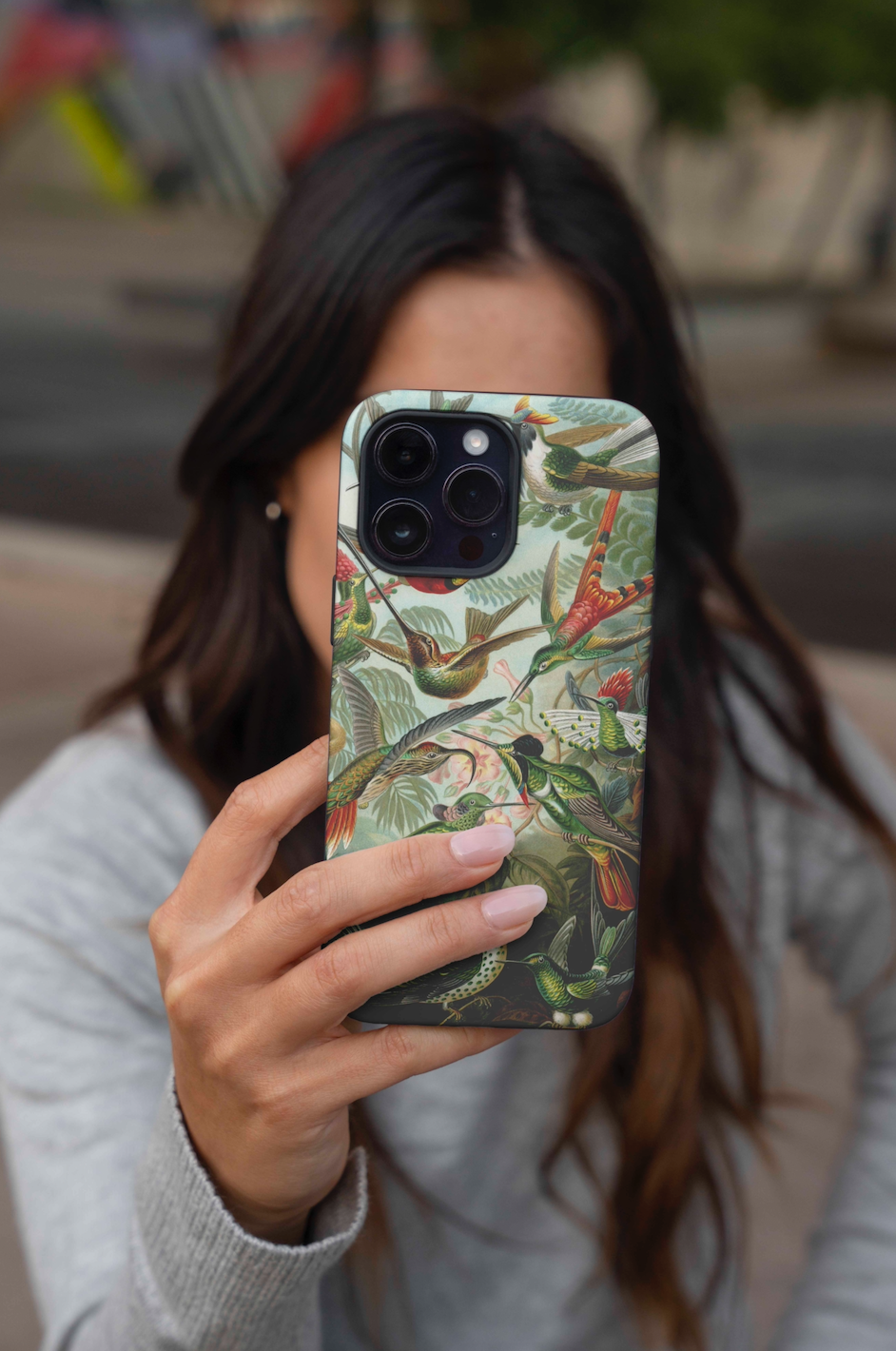 Lifestyle shot of someone holding an ARTSNOB phone case featuring a vintage hummingbird print, highlighting the vibrant colors and artistic design.