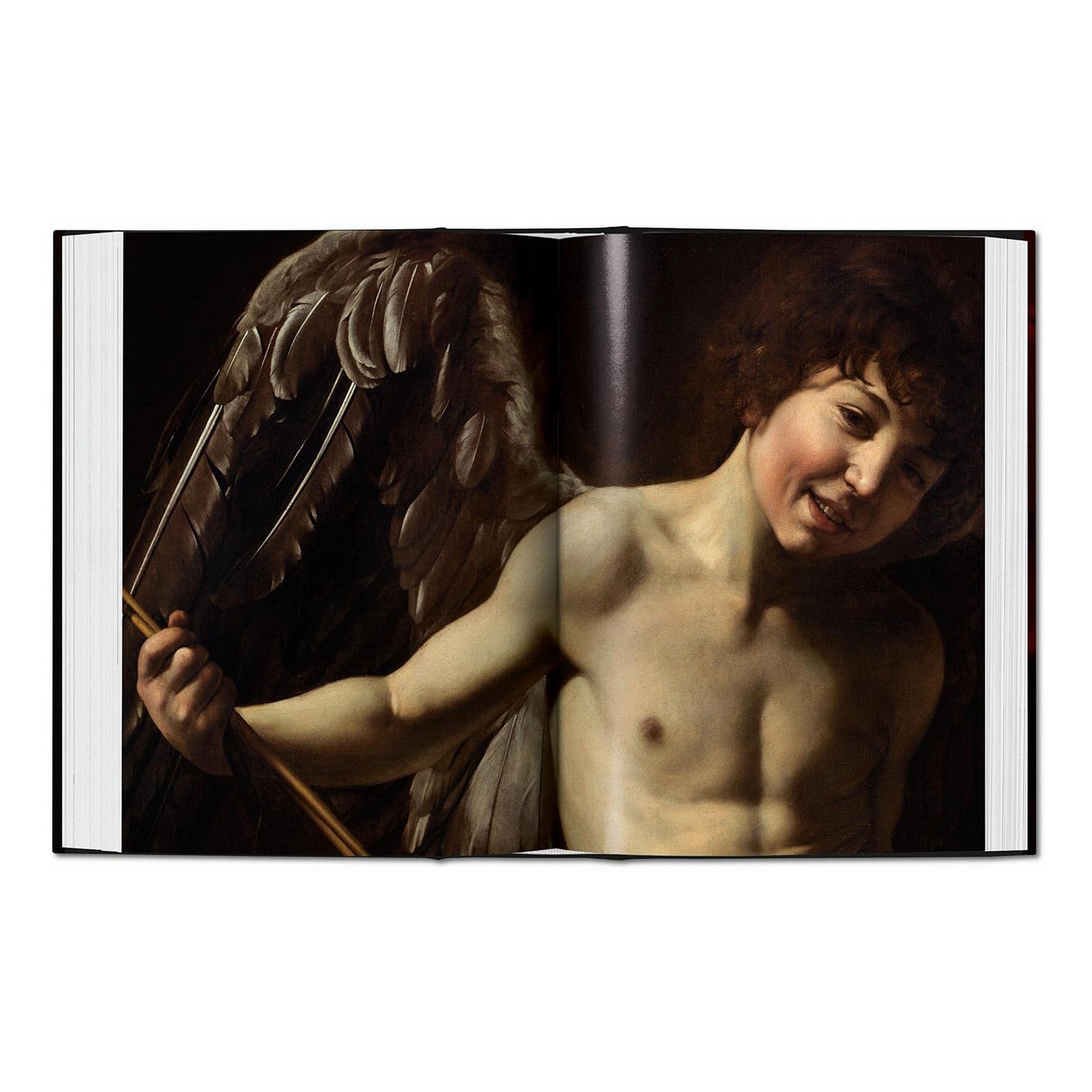 Interior spread of the Caravaggio complete works book, featuring the masterpiece 'Amor Vincit Omnia', a perfect example of fine art for a luxury home library.