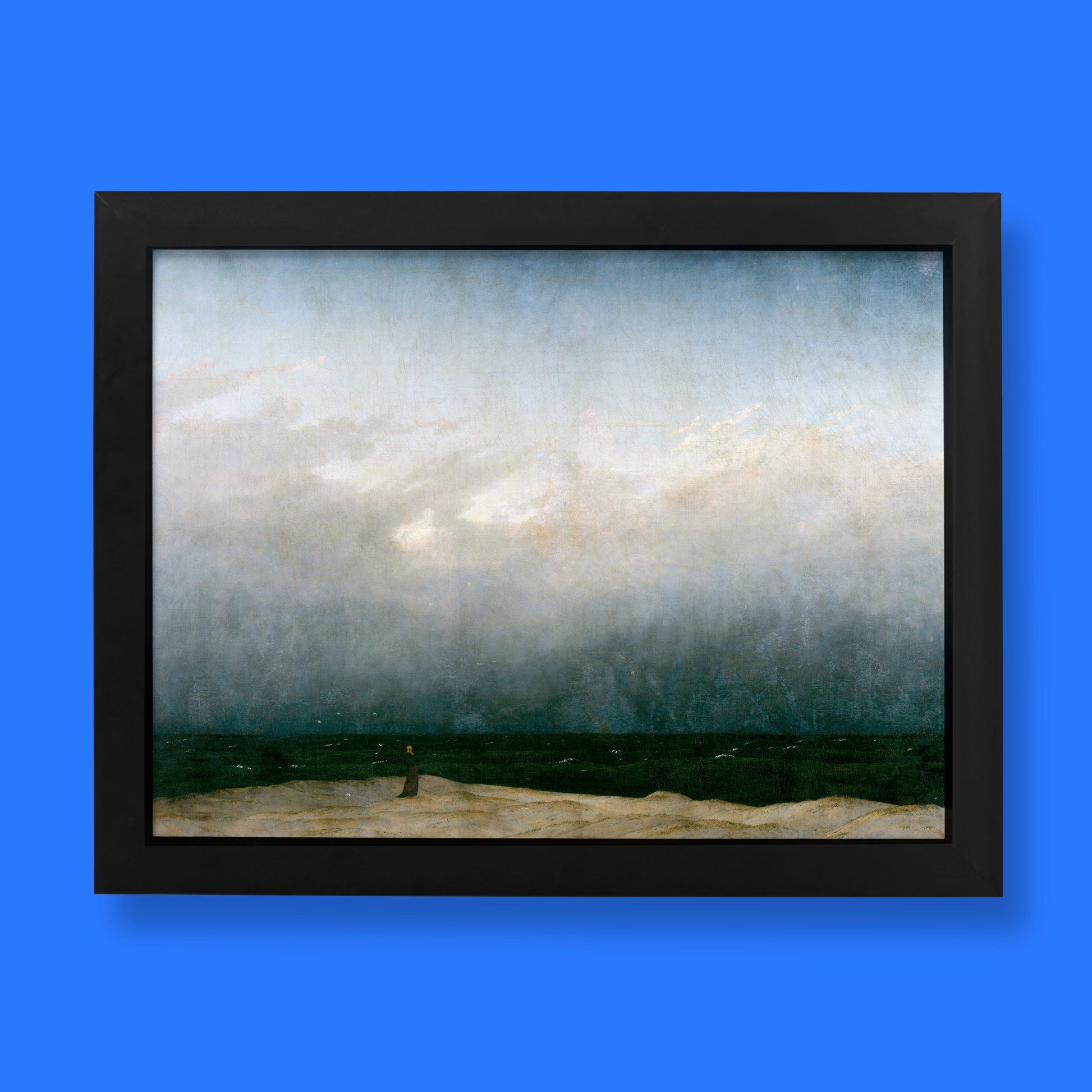 Caspar David Friedrich Monk by the Sea fine art print, featuring a solitary robed figure standing on a sandy shore before a vast, stormy ocean and dramatic grey sky