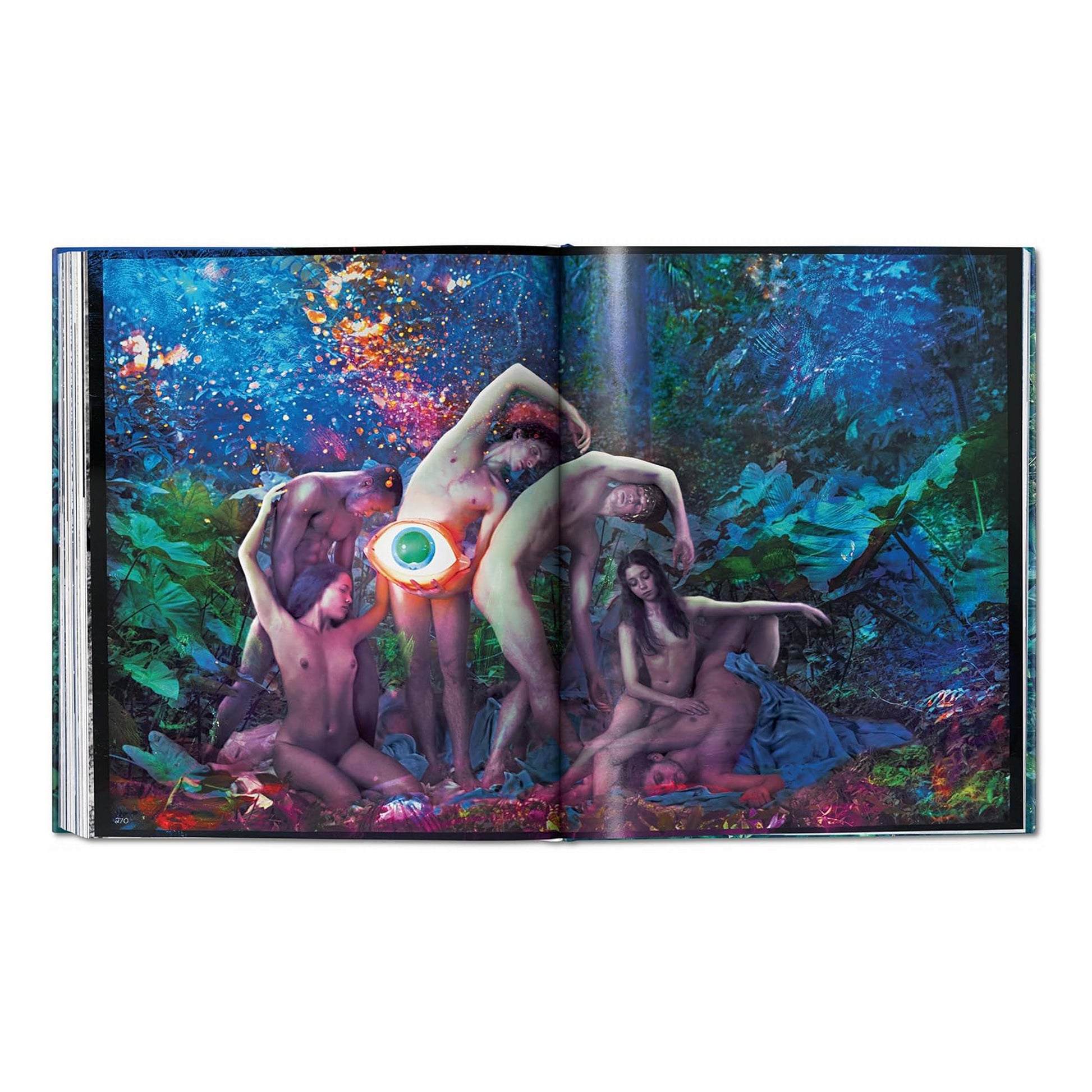 A double-page spread from the David LaChapelle Good News hardcover book, showing a surreal photograph of multiple figures in a lush, tropical setting with a glowing orb.