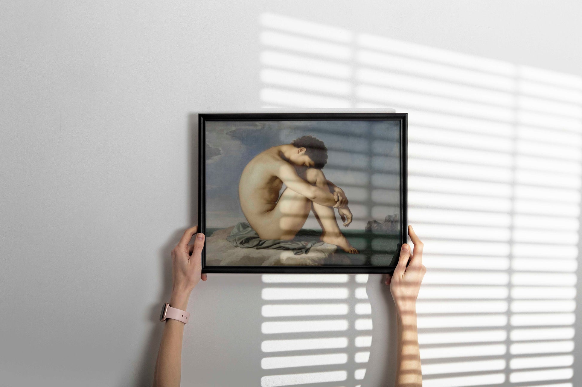A fine art print of Hippolyte Flandrin's "Young Male Nude Seated Beside the Sea" displayed in a sleek black frame on a white wall, a perfect piece of elegant wall decor.