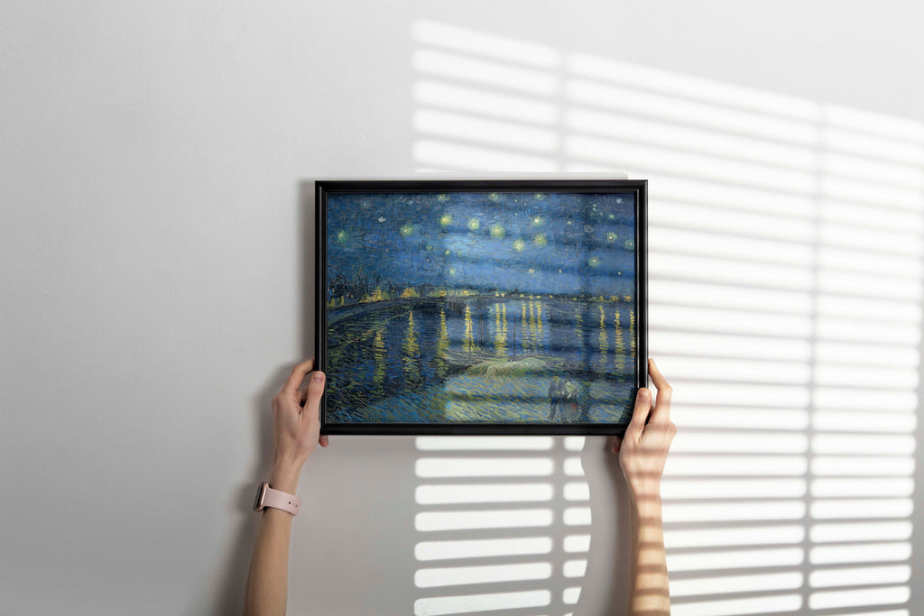 An elegant home decor image showing a high-quality framed art print of Van Gogh's "Starry Night Over the Rhône" displayed against a white wall.