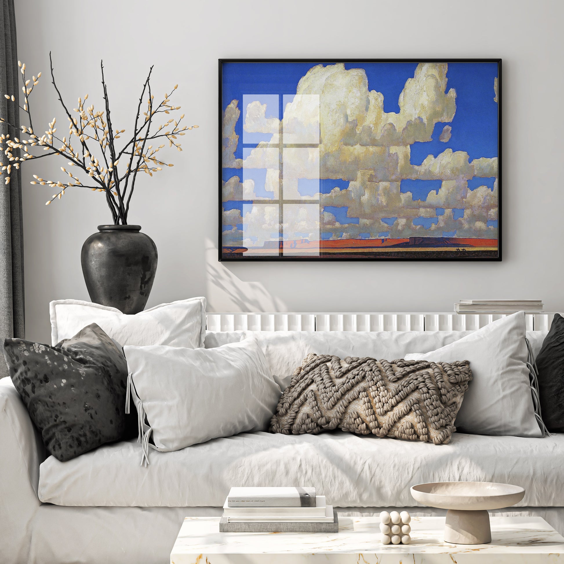 A large Maynard Dixon Cloud World art print framed on a minimalist living room wall above a neutral sofa.