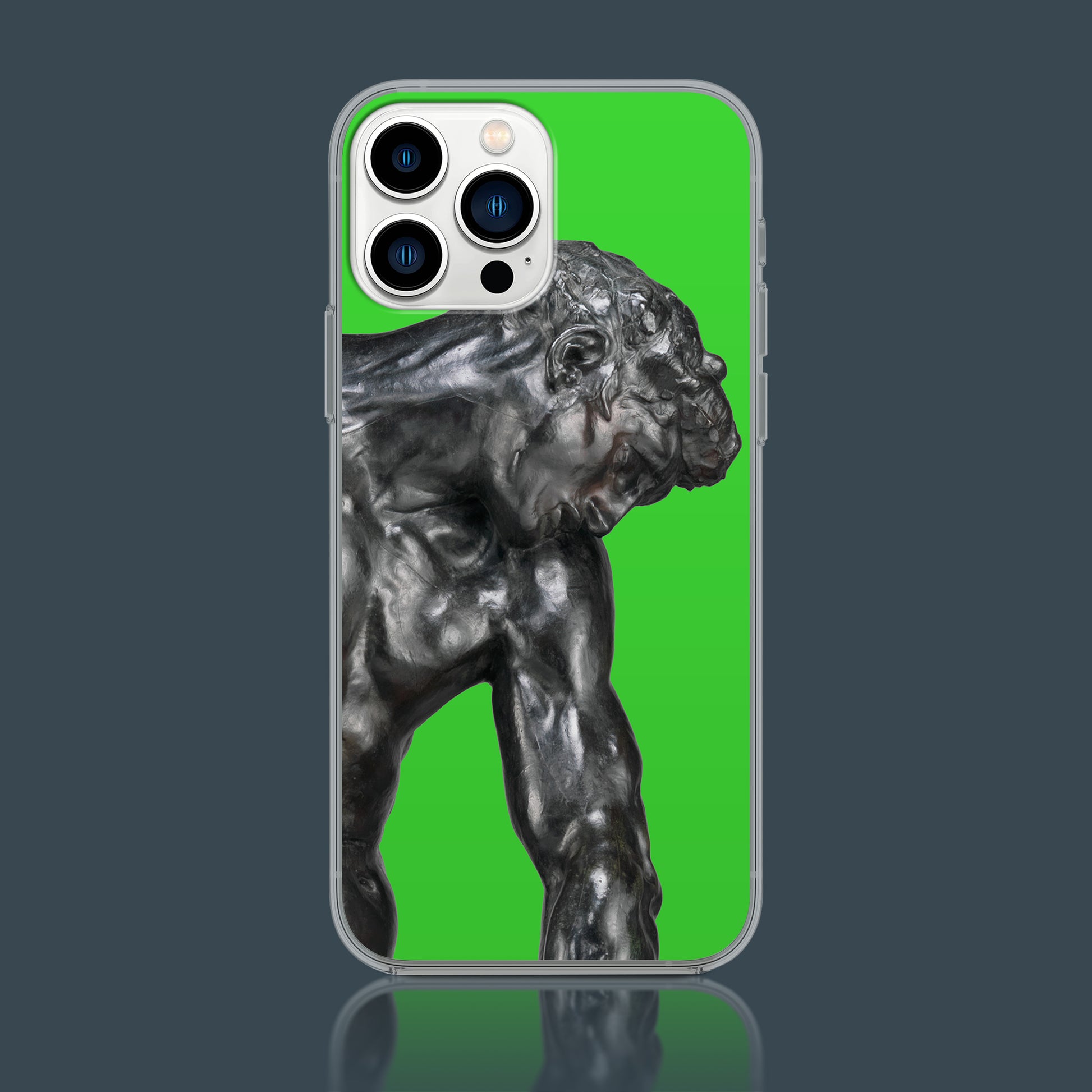 A clear plastic iPhone case with a green screen background. The phone displays a close-up image of Auguste Rodin's bronze sculpture, "Adam," from the chest up, with his head bowed and arms slightly bent. The phone case and the phone itself are reflected on a dark, polished surface.