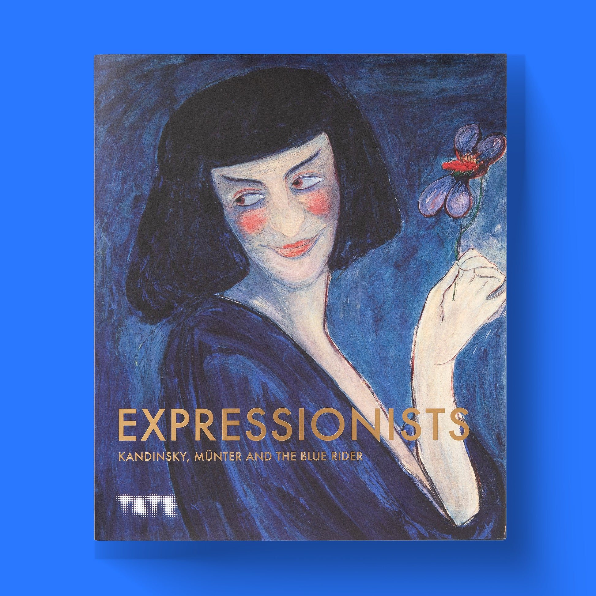 A close-up shot of the front cover of the Tate's 'Expressionists: Kandinsky, Münter and The Blue Rider' hardcover art book, featuring the vibrant portrait 'The Dancer Alexander Sacharoff' by Marianne Werefkin.