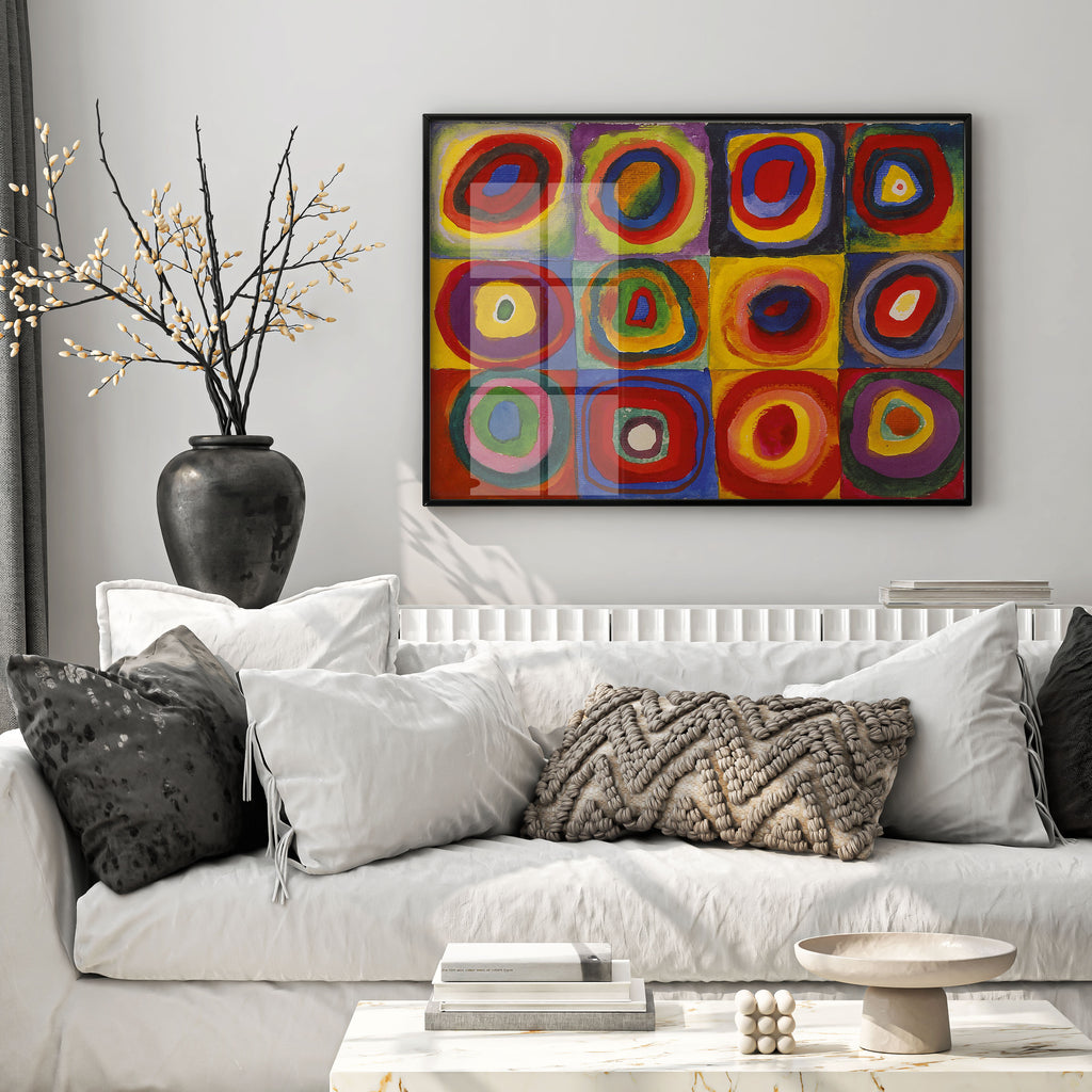 A colourful abstract canvas print with concentric circular patterns in red, yellow, blue, green, and purple, hanging on a light grey wall above a white sofa with decorative pillows.